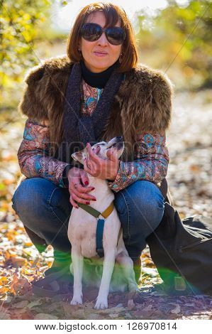 portrait of a woman with a dog on holiday in the autumn park  age of 40 years