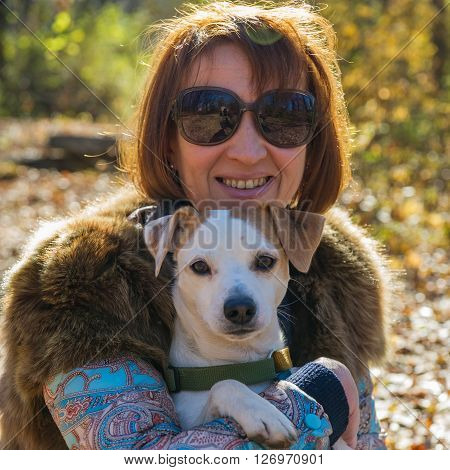 portrait of a woman with a dog on holiday in the autumn park  age of 40 years