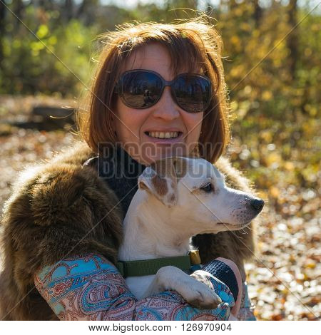 portrait of a woman with a dog on holiday in the autumn park  age of 40 years