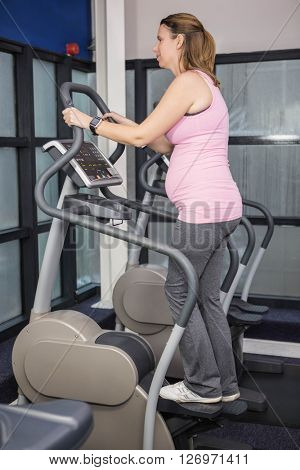 Pregnant woman on crosstrainer at the gym