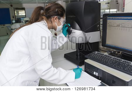 Woman scientist looking through microscope for lab analysis