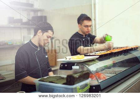 male cooks preparing sushi in the restaurant kitchen.