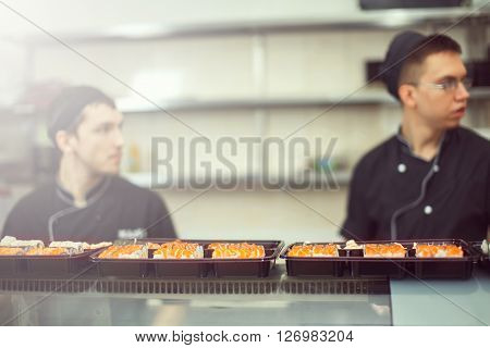 male cooks preparing sushi in the restaurant kitchen.