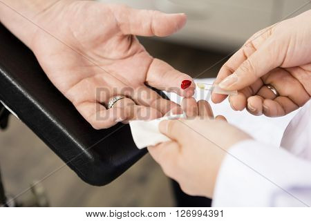 Doctor Taking Blood Sample Of Patient In Clinic