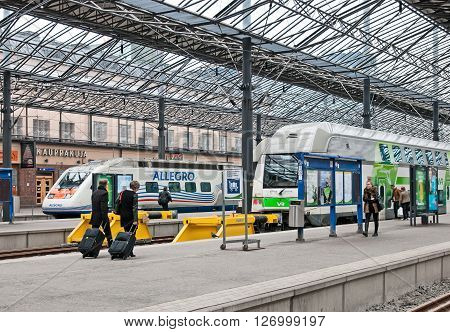 HELSINKI, FINLAND - APRIL 23, 2016: The Central Railway Station. People walk along the platform near the double decker trains and Allegro Train