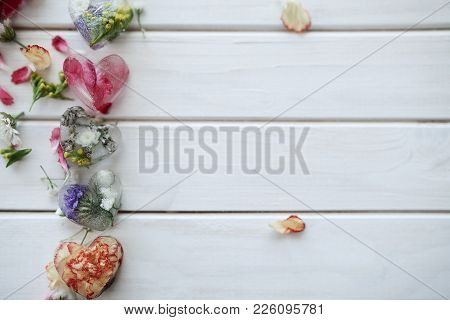Petals And Cubes Of Ice Of Heart With Flowers Inside On A White Wooden Background