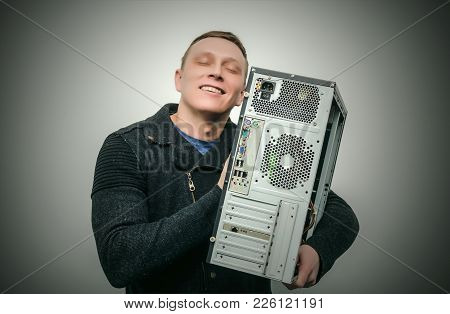 Happy Computer Tecnician Man Hugs A Computer Isolated On Dark Background. Gamer Man Love His Compute