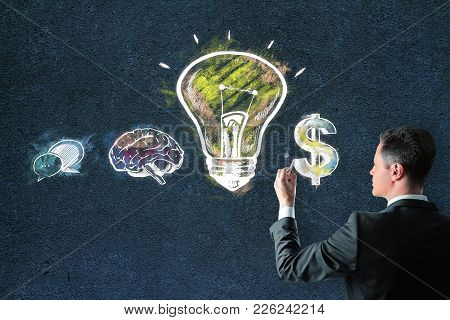 Handsome European Businessman Drawing Creative Business Sketh On Concrete Wall Background. Leadershi