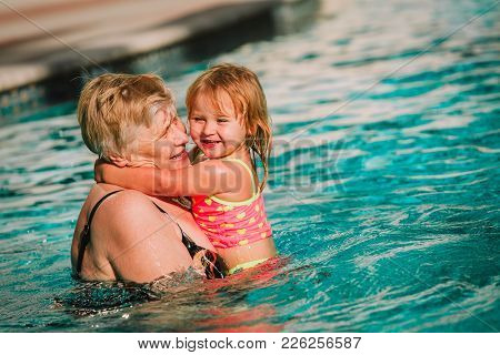 Grandmother And Granddaughter Swimming At Pool, Active Retirement