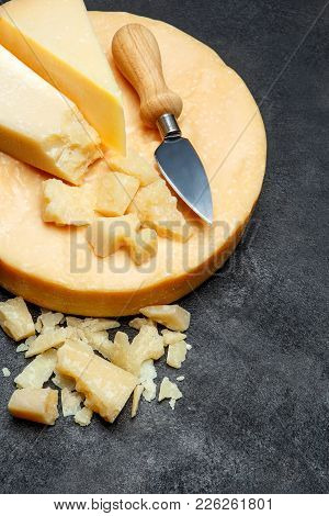 Head Of Parmesan Or Parmigiano Hard Cheese And Pieces On Concrete Background Or Table