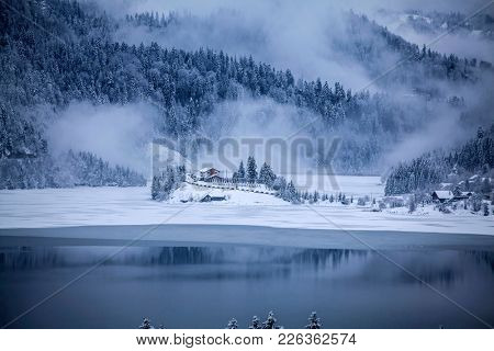 Frozen lake and pine trees in snow at Colibita. Romania early morning winter secen.
