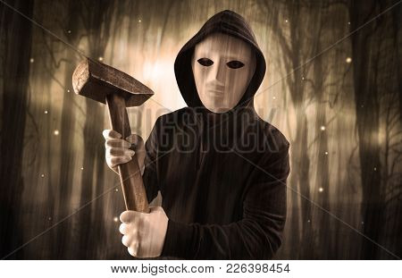 Masked armed hitman in dark thick forest with foggy mysterious concept
