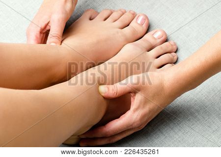 Close Up Of Hands Applying Pressure On Female Ankle.physiotherapist Massaging Feet With Thumbs.