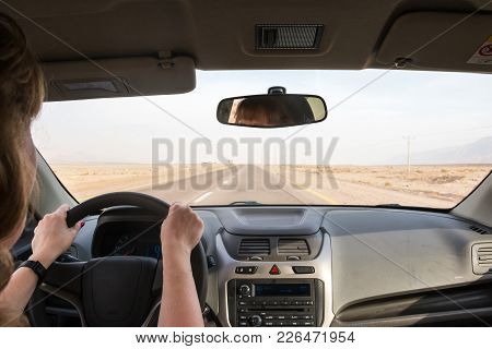 The Hand Of A Girl On The Handlebars In A Saloon Car And The Road In Desert Ahead