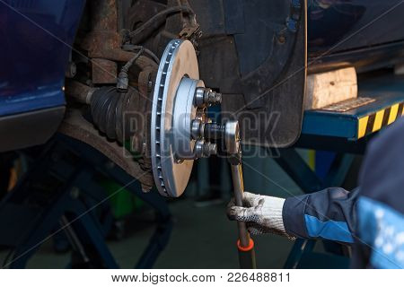 The Man Twists The Screws On The Disk, The Machine. Disk Brake Repair In The Car.