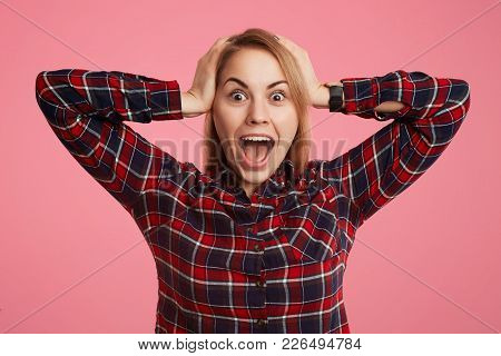 Frightened Shocked Young Female Opens Mouth Widely And Exclaims In Terror, Doesn`t Anticipate To See