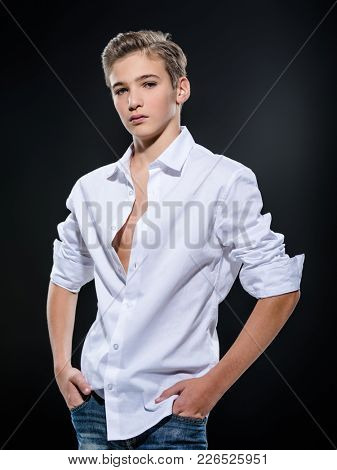 Photo of teenage handsome guy posing at studio. Fashion portrait of cute pretty teen boy