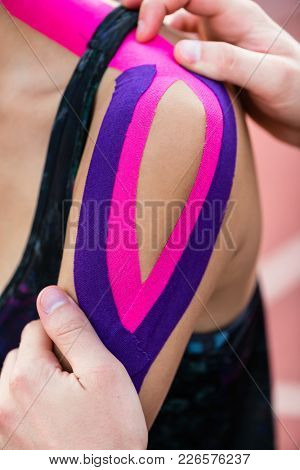 Woman taping with therapeutic tape on cinder track of sports stadium