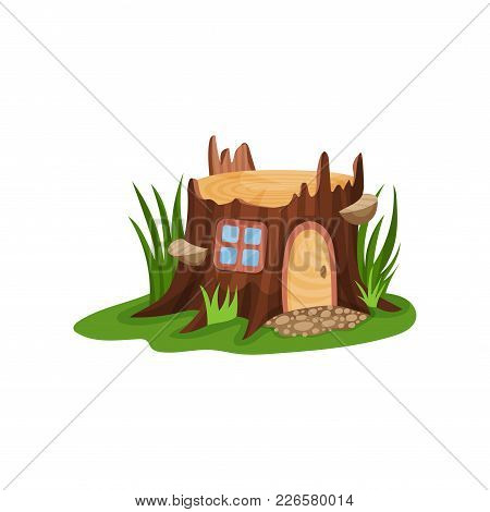 Small Fairy-tale House In Form Of Old Stump Surrounded By Tall Green Grass. Home With Wooden Arched 