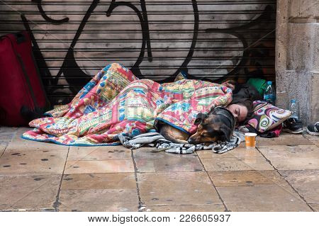 Barcelona, Spain, February 4, 2018 A Young Guy, A Girl And A Dog Covered With Blankets Sleeping On T