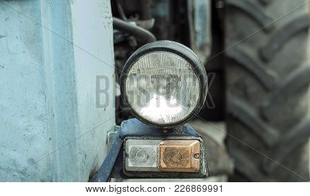 Headlight Closeup On The Tractor. Half Of Old Rusty Green Historical Vintage Tractor With Light Tire