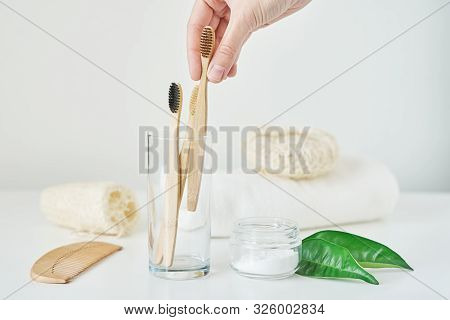 Woman Hand Take Wooden Bamboo Toothbrush In Bathroom Interior. No Plastic Zero Waste Concept. Eco Fr