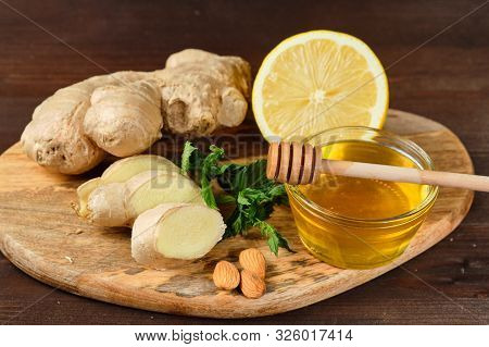 Honey With Ginger, Lemon And Mint And Nuts On Wooden Board And Grey Background.