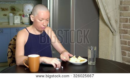 Proper Nutrition After Chemotherapy. A Bald Woman At The Table Drinks Pills While Eating.
