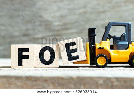 Toy Forklift Hold Letter Block E  To Complete Word Foe On Wood Background