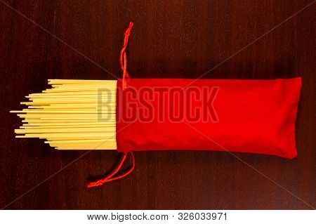 Italian Pasta. Raw Yellow Spaghetti In A Red Holiday Velvet Sack. Dry Pasta Or Cappellini On A Brown