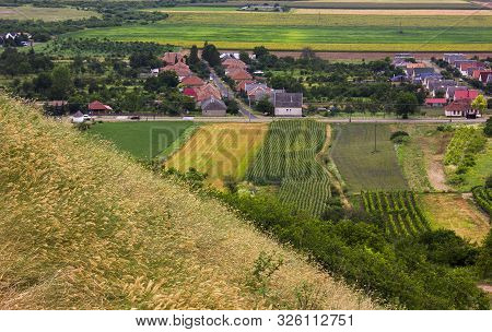 Small Village In A Valley. Hills, Mountains And Fields Around. Summer Day. Picture Taken From The Si