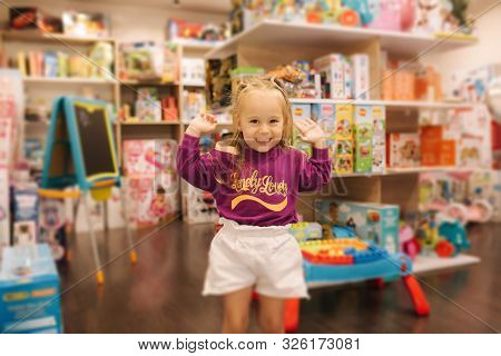 Happy Little Girl Walkning In Toy Store. Cute Girl Choose Toy. Adorable Female In Kids Mall