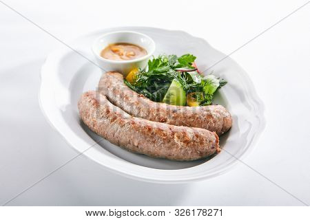 Macro shot of Munich sausages for frying made from pork and beef with mustard sauce and mixed salad isolated. Traditional German rostbratwurst, wurst or bratwurst with vegetables and greens closeup