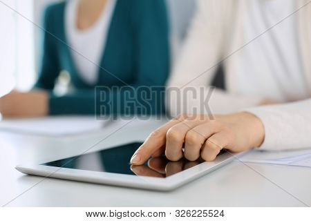 Businesswoman Pointing At Tablet Computer Screen While Giving Presentation To Her Female Colleague. 