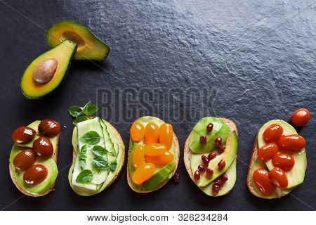 Top View Avocado Halves And Vegetarian Fresh Sliced Canapes With Black Copy Space Flat Lay Backgroun