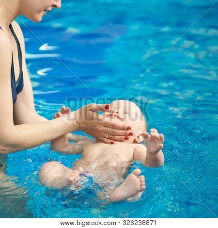 Swimming Lessons For Newborns With Mothers In Paddling Pool. Blue Turquoise Water On Background. Par