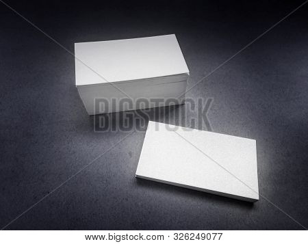 Stack Of Blank White Business Cards On A Dark Vintage Background. Mockup Of Visiting Cards Of Shiny 