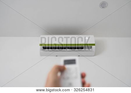 Mans Hand Using Remote Controler. Hand Holding Rc And Adjusting Temperature Of Air Conditioner Mount