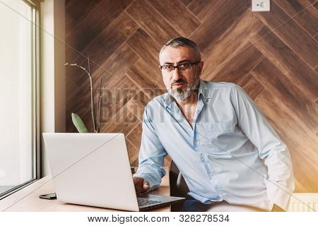Handsome Middle Aged Man Working On Computer In A Cafe. Business, Modern Concept
