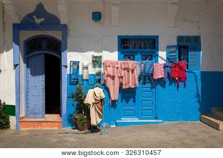 Facade of a traditional house with laundry hanging outdoors in the medina of Assilah, Morocco