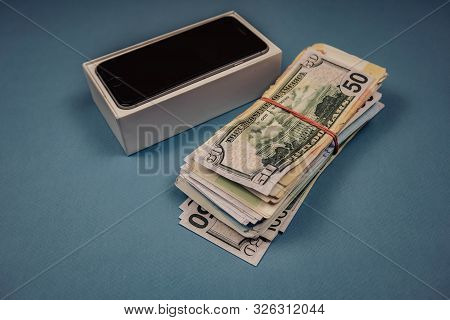 Apple Iphone Devices And Dollars On A Blue Monophonic Background. Voronezh, Russia - May 3, 2019