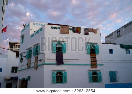 Traditional Moroccan carpets hanging on the facade of a carpet store in twilight in Asilah, North Morocco