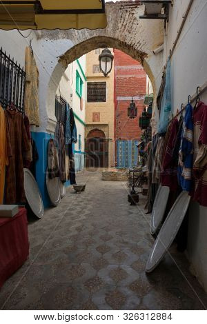 Narrow old street  with merchandise in the medina of Asilah, Morocco