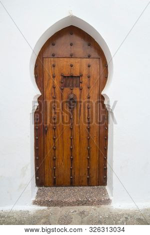 Old wooden door with brass decoration in the medina of Asilah, Morocco