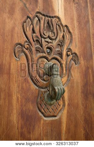 Old knocker in the shape of a hand on a wooden door in Asilah, Morocco