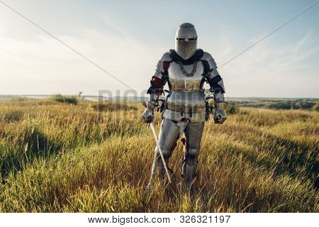 Knight in armor and helmet holds sword