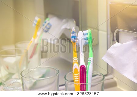 Set Of Brushes For Teeth, Teethbrushes For All Family Image In Bathroom, In A Glass Cup. Multicolour