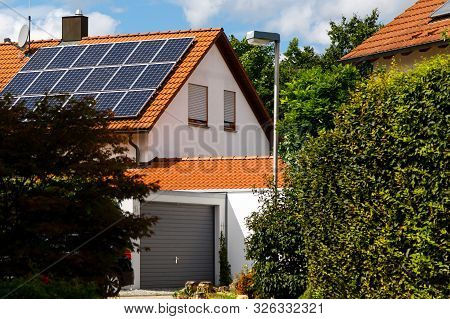 Solar Panels On The Tiled Roof Of A Building On A Bright Sunny Day. The Concept Of A Good Investment