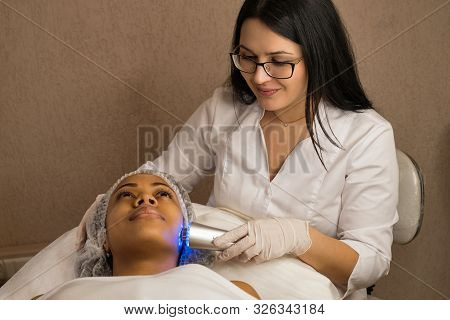 Ultrasound Chromotherapy. Hardware Cosmetology. Cosmetologist Is Professional With Patient In Office