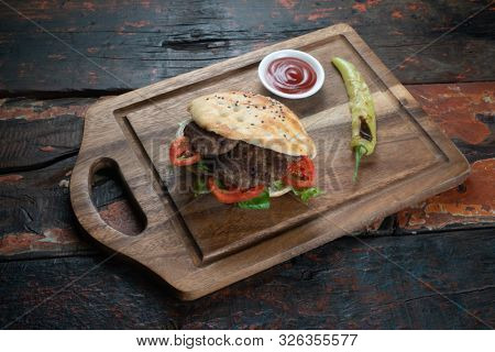 Turkish Kofte Ekmek. Meatball Sandwich with tomatoes, onion and green pepper isolated on rustic wooden background